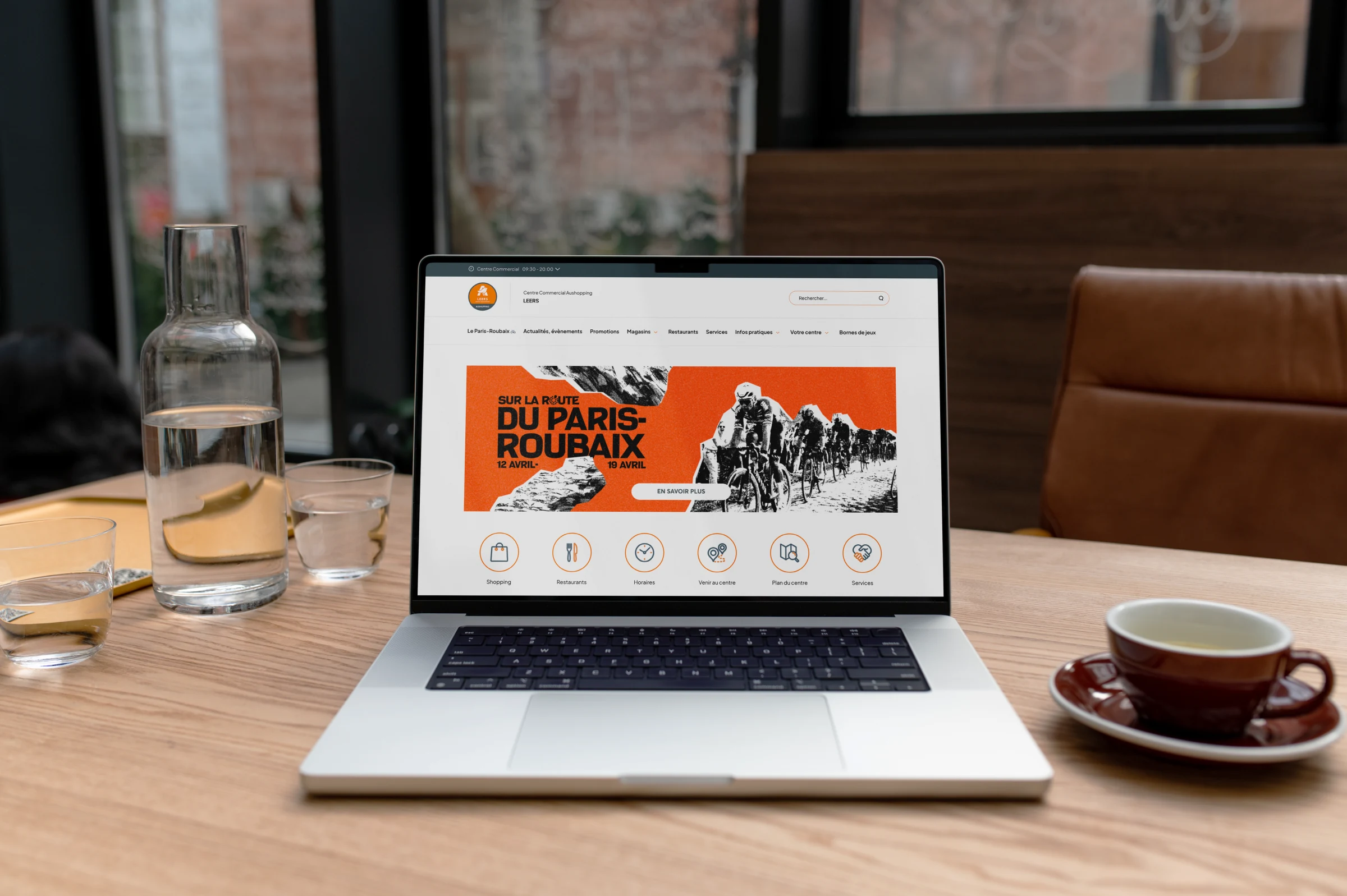 Aushopping, mockup laptop sur table de café, page web campagne Sur la route du Paris-Roubaix.
