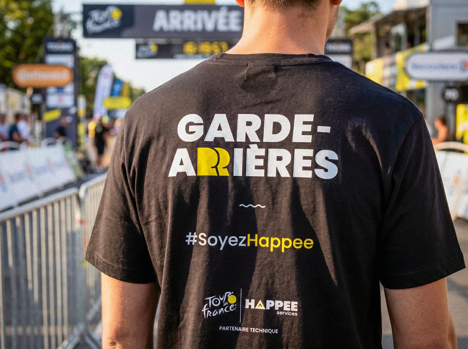 T-shirt staff Happee noir, recto logo discret, dos grand mot Garde-arrière en blanc avec le motif RR magenta et jaune.